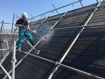 高圧洗浄をし、屋根の汚れを落としている作業員