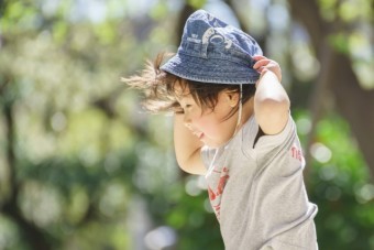 強い風で帽子を飛ばされそうになる子供