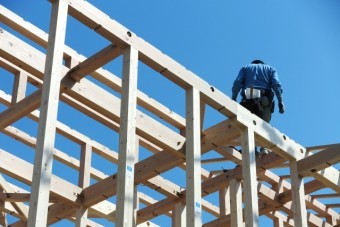 建築中のお家の骨組みの上に立つ職人