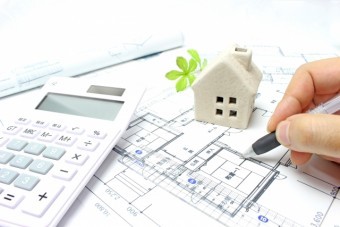 設計図・住居の模型・電卓が置かれたデスクの上