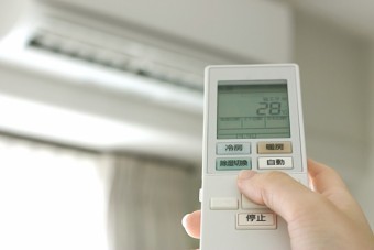 エアコンにリモコンをかざす人