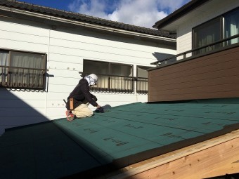 ルーフイング材を張っている作業員