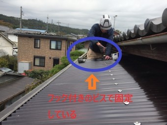 フック付きのビスで波板を固定する作業員