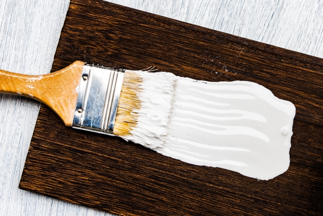 白色のペンキを木の板に塗っているイメージ