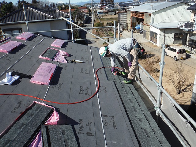 屋根材を専用のくぎ打ち機を使用し止めている作業風景