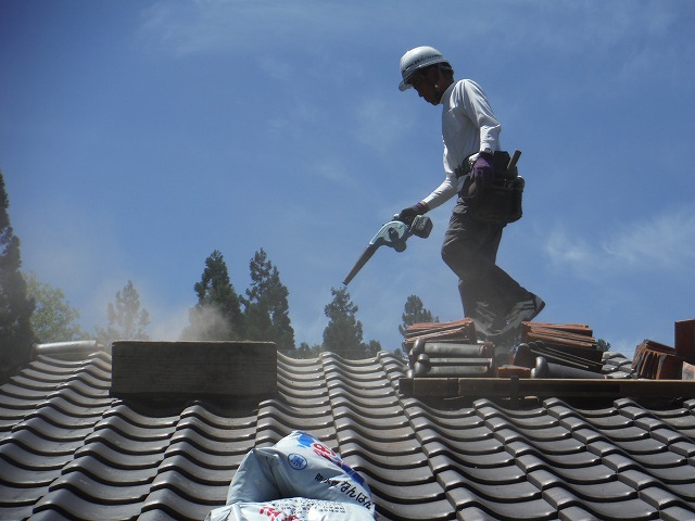 空気の出る機械(ブロワ―)で屋根の埃を飛ばしている作業員