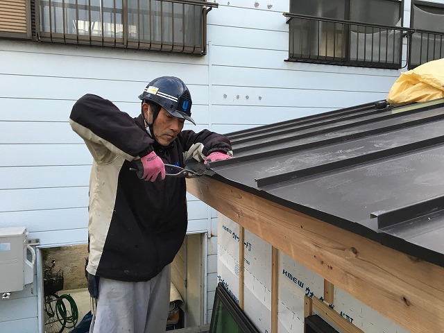 板金屋根の軒部分を加工している職人