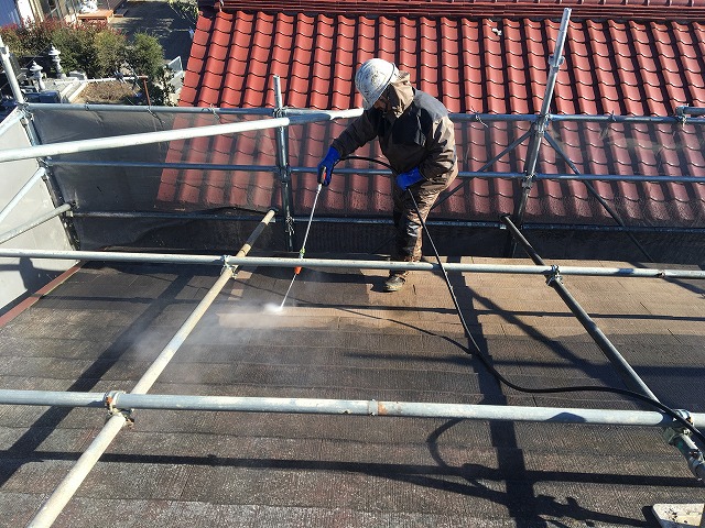 高圧洗浄機を使い、屋根の洗浄を行っている作業員