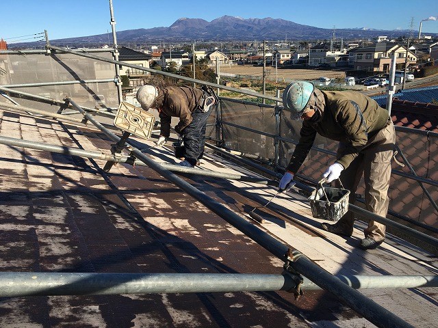 屋根の裏側で下地塗料のシーラー剤を塗っている作業員