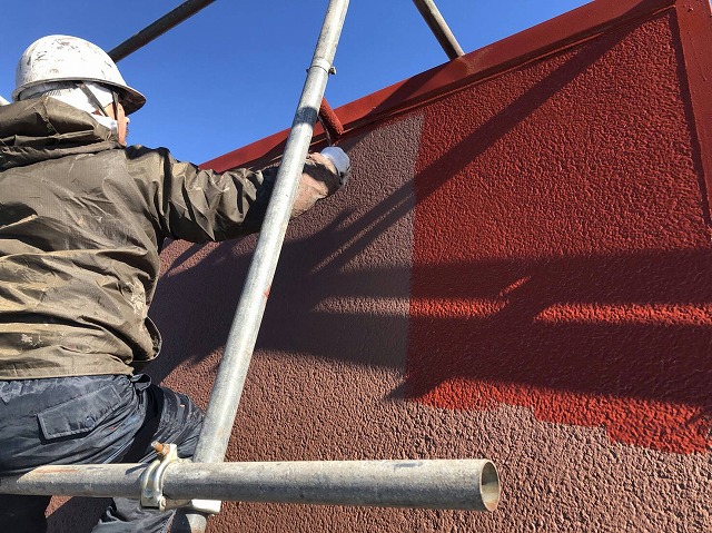 正面の屋根面を塗装している作業員
