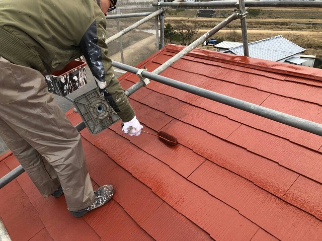 裏側の屋根面を塗装している作業員